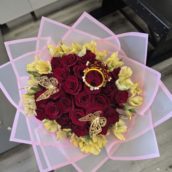 Bouquet of red roses with yellow flowers wrapped in pink paper