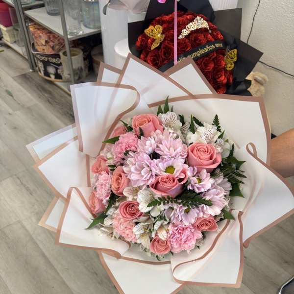 Pink roses and daisies wrapped in white paper with blush trim