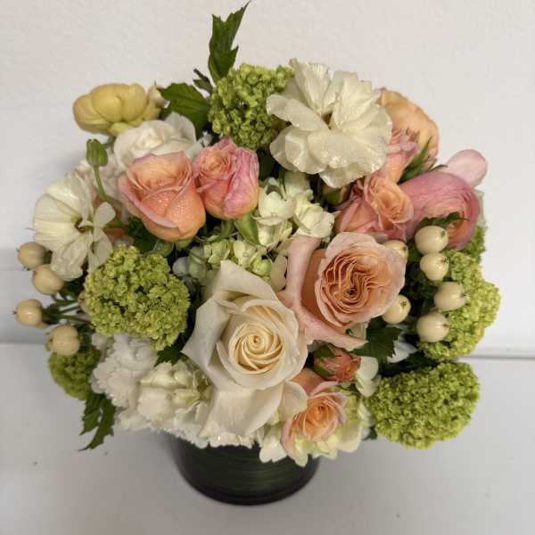 Bouquet of peach and white roses with green hydrangeas in a black vase