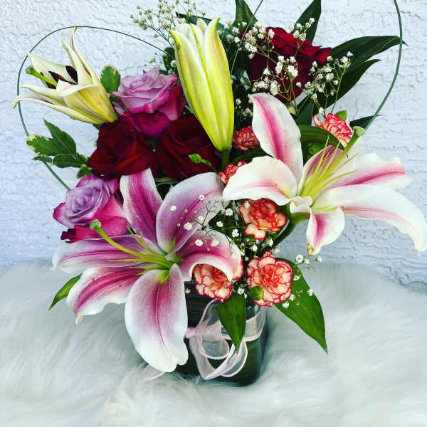 Bouquet of lilies and roses in a glass vase with pink ribbon
