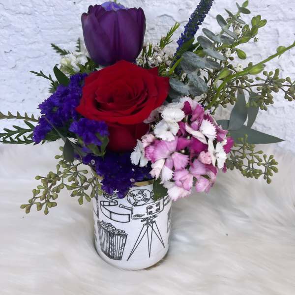Red rose and purple tulip arrangement in a printed ceramic vase
