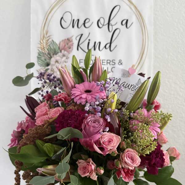 Pink mixed flower bouquet in a glass vase with a gift card