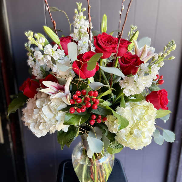 Red roses and white flowers arranged in a clear glass vase