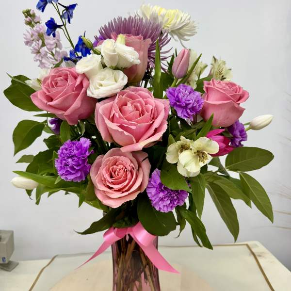 Pink and white mixed bouquet in a pink glass vase with a ribbon