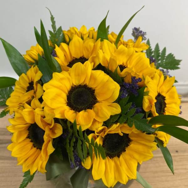 Bouquet of yellow sunflowers with purple filler in a vase