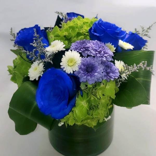 Blue roses and purple and white daisies in a green hatbox