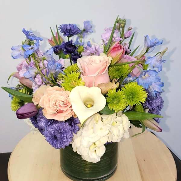 Mixed bouquet in a dark green vase with pink, purple, white, and blue flowers