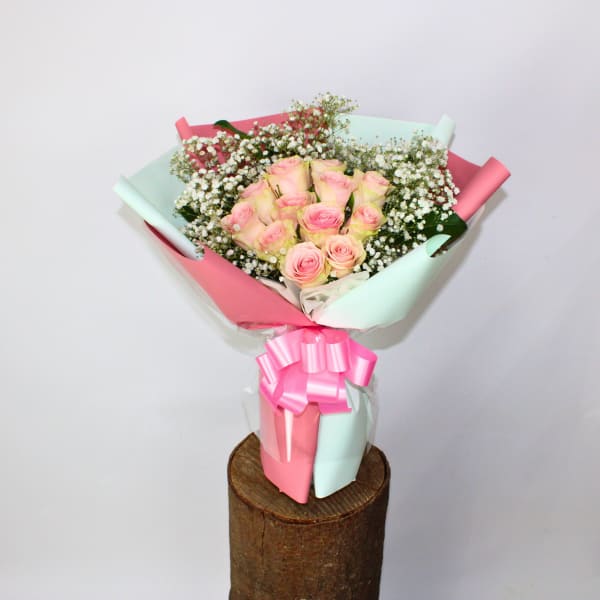 Bouquet of pink roses wrapped in pastel pink and mint paper