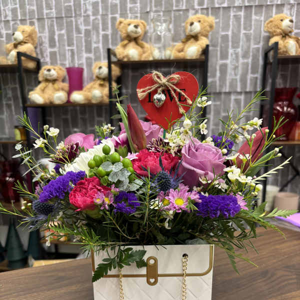 Mixed bouquet in a white gift bag with a red heart topper
