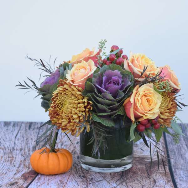 Mixed bouquet in a glass vase with a small pumpkin beside it