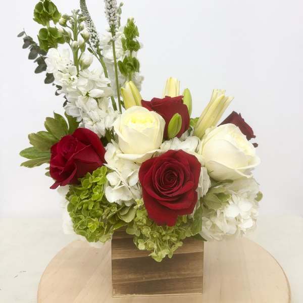Red and white roses with white hydrangeas in a wooden box