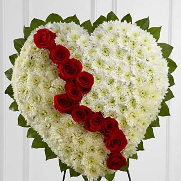 Heart-shaped white floral tribute with a diagonal line of red roses