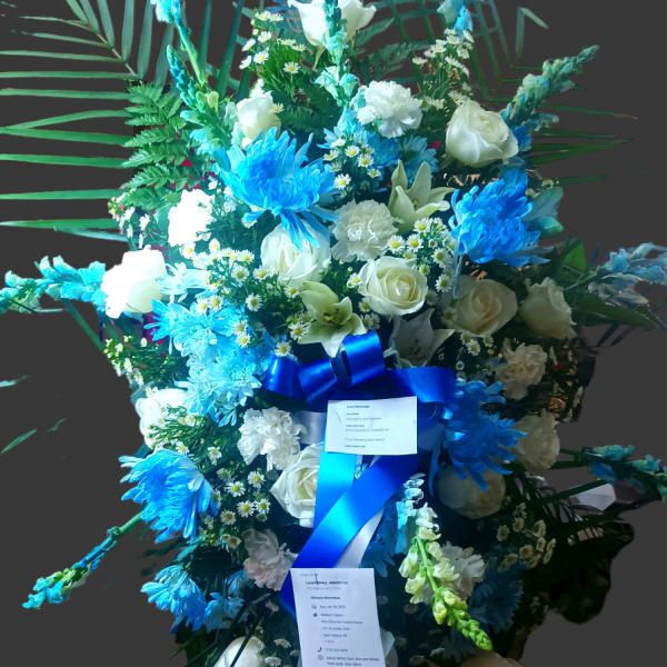 Tall blue and white floral standing spray on an easel with ribbon