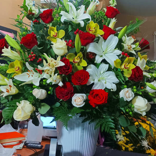 Large mixed bouquet of red and white flowers in a white vase