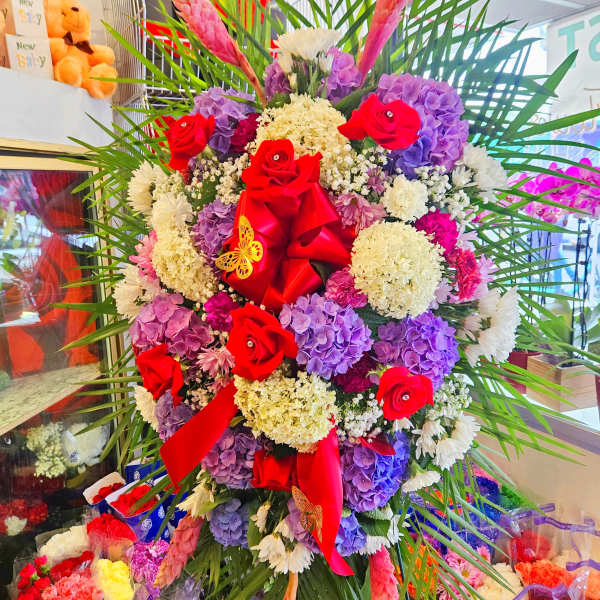 Large standing floral arrangement with red roses and purple hydrangeas
