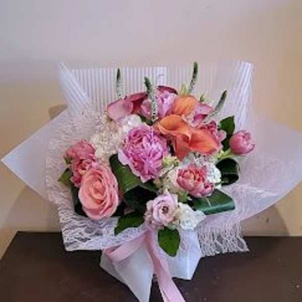 Pink and peach bouquet wrapped in white paper with a pink ribbon