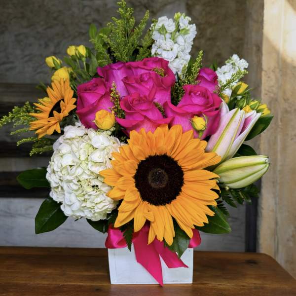 Bright mixed bouquet with pink roses, sunflowers, white hydrangeas, and lilies in a white box