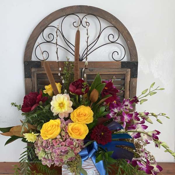 Mixed floral arrangement with yellow roses and purple orchids in a white vase