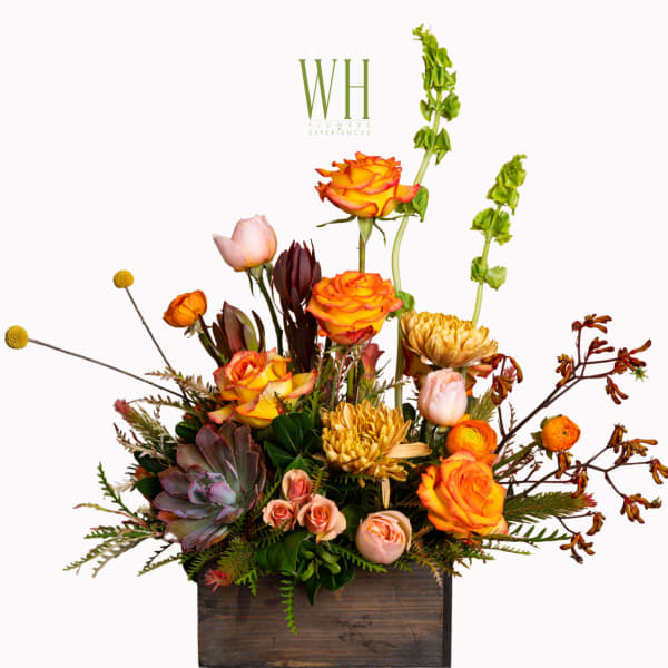 Mixed floral arrangement in a wooden box with orange roses and pale pink blooms