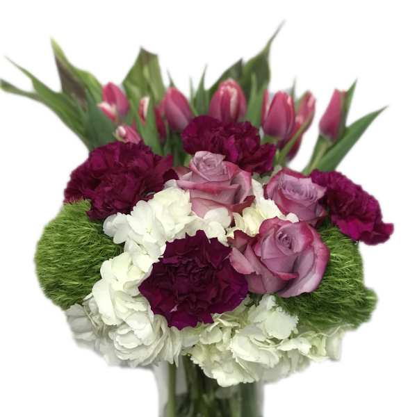 Bouquet of pink tulips, roses, and carnations in a glass vase