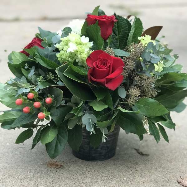 Red roses and pale green blooms in a black container