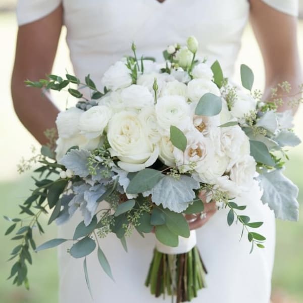 Bride holding a white bouquet with greenery