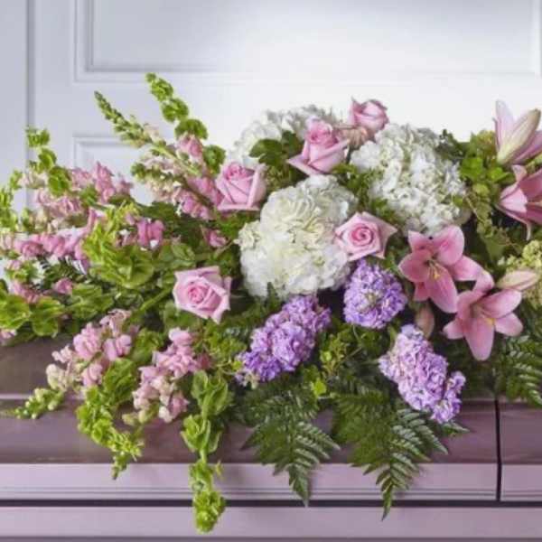 Pink and white floral casket spray with lilies, roses, and hydrangeas