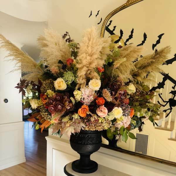 Large autumn floral arrangement in a black urn with pampas grass and mixed blooms