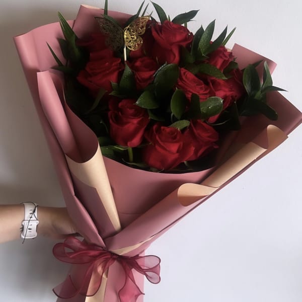 Bouquet of red roses wrapped in pink paper with a ribbon