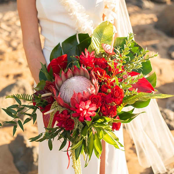 Bride holding a red tropical bouquet with a large protea bloom