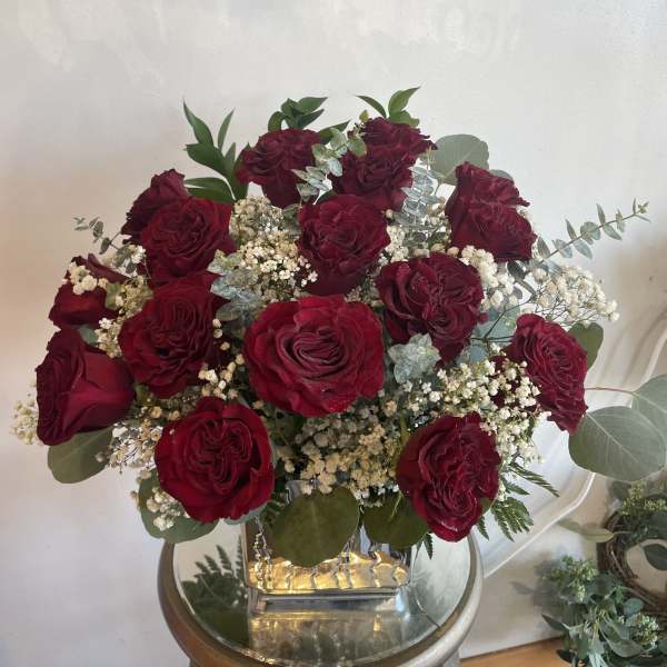 Bouquet of deep red roses with white filler flowers in a glass vase