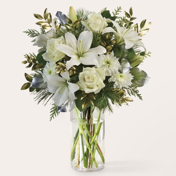 White lilies and roses arranged in a clear glass vase