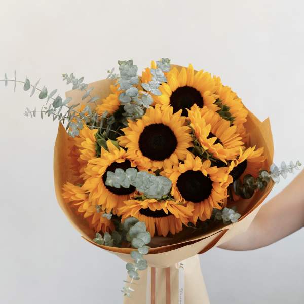Bouquet of sunflowers wrapped in tan paper with eucalyptus