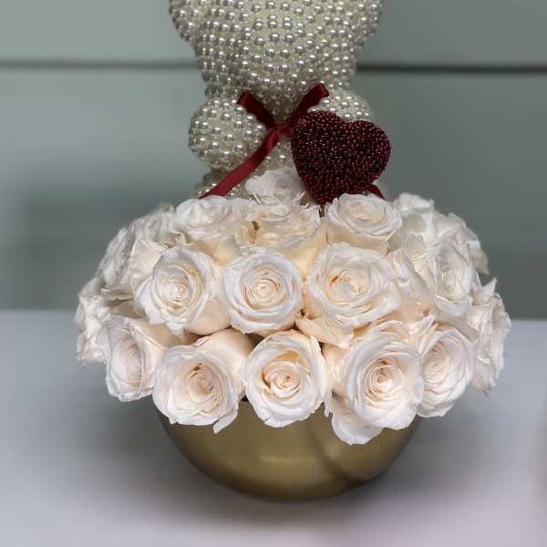 White rose arrangement with pearl teddy bears in a gold vase
