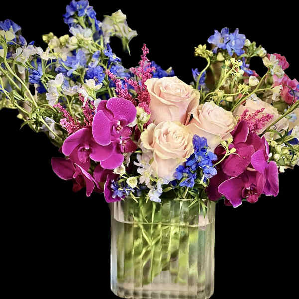Pink roses and purple orchids in a clear glass vase