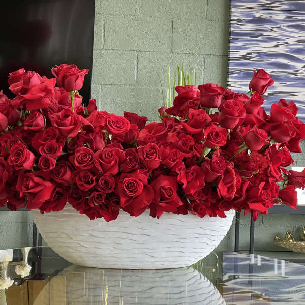 Large arrangement of red roses in a white bowl vase