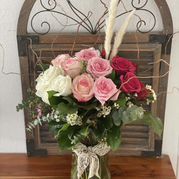 Bouquet of pink, white, and red roses in a glass vase