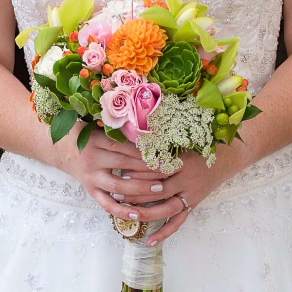 Bride holding a colorful bouquet with pink roses and orange blooms
