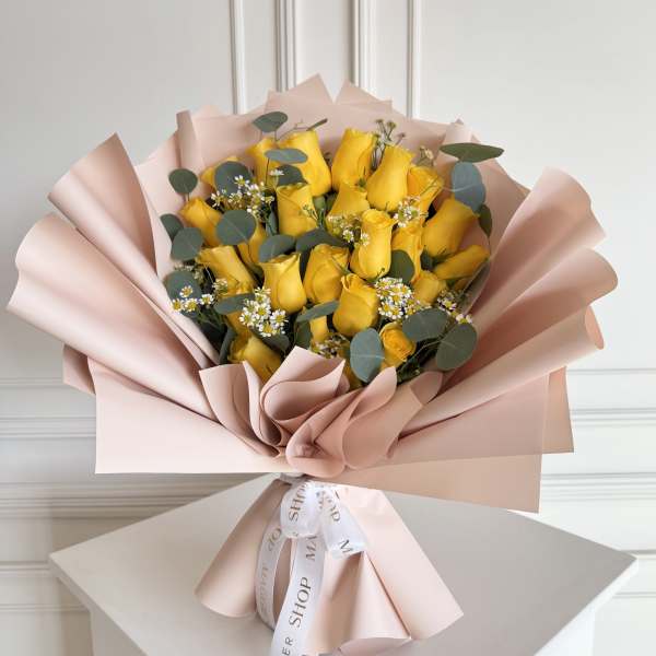 Bouquet of yellow roses wrapped in blush pink paper