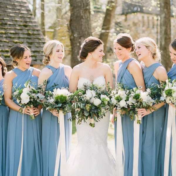 Bride and bridesmaids holding white and green bouquets outdoors