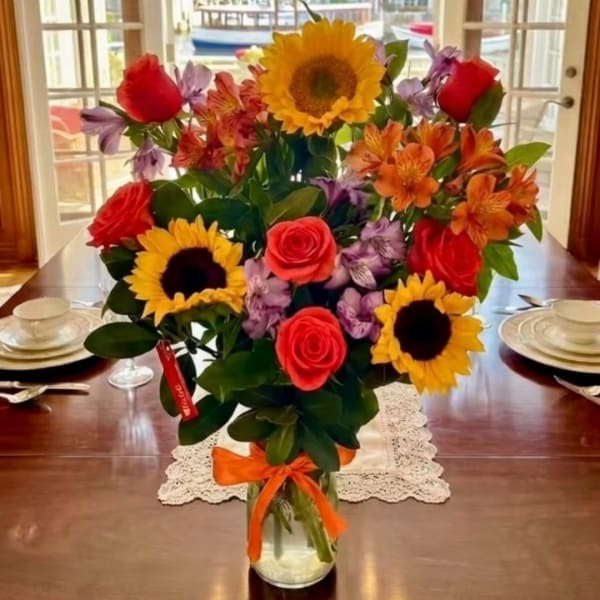 Bouquet of sunflowers, roses, and alstroemeria in a glass vase