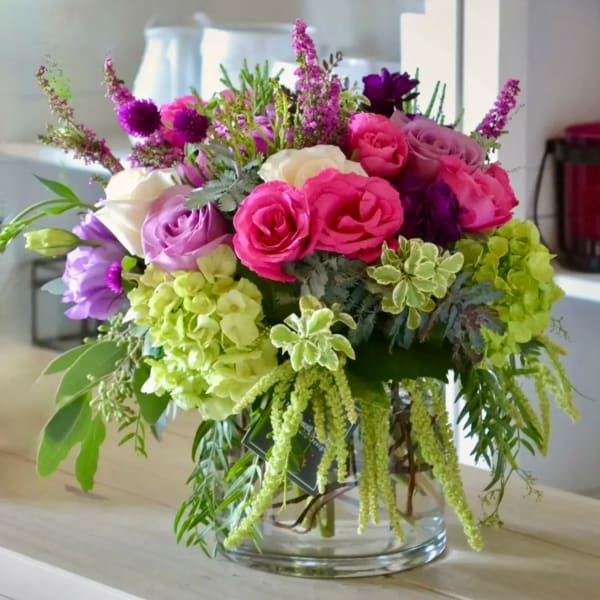Bouquet of pink, purple, and white flowers in a clear glass vase
