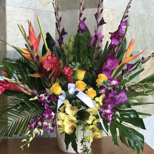 Tropical flower arrangement with orchids and roses in a white vase