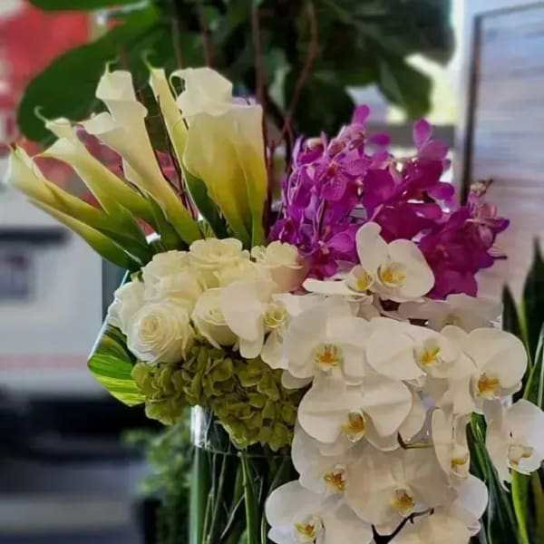 White calla lilies, orchids, and roses in a glass vase
