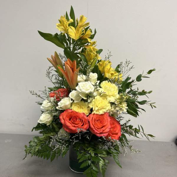 Mixed bouquet of roses, lilies, and carnations in a glass vase