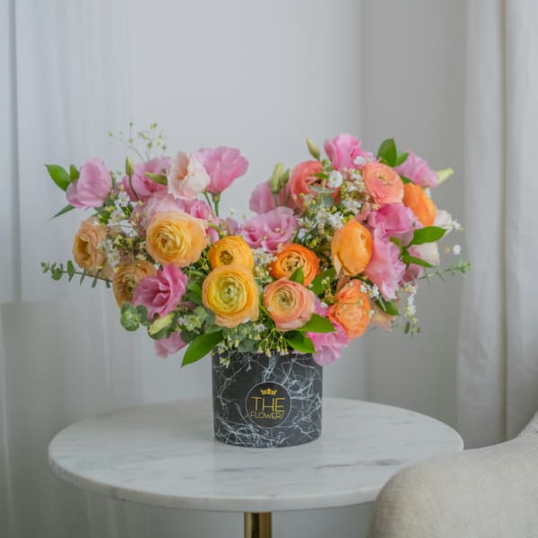 Pink and orange mixed flower arrangement in a black vase
