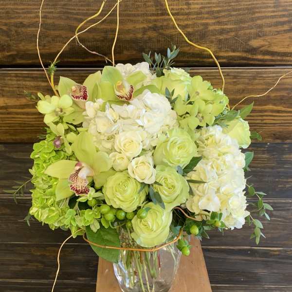 Lime green and white floral arrangement in a clear glass vase