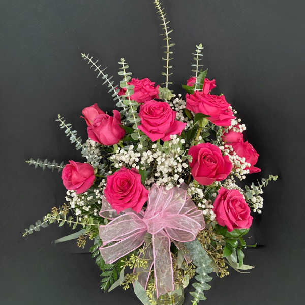 Pink rose bouquet with baby's breath in a glass vase and pink ribbon