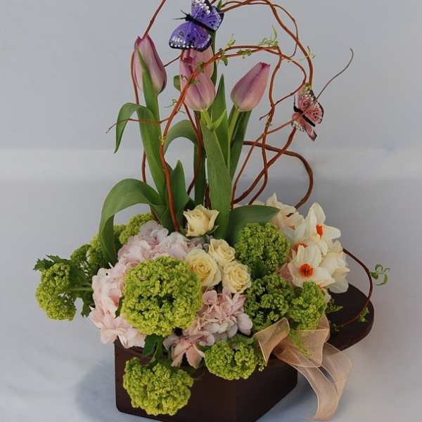 Pink tulips and mixed flowers in a dark box with decorative butterfly picks