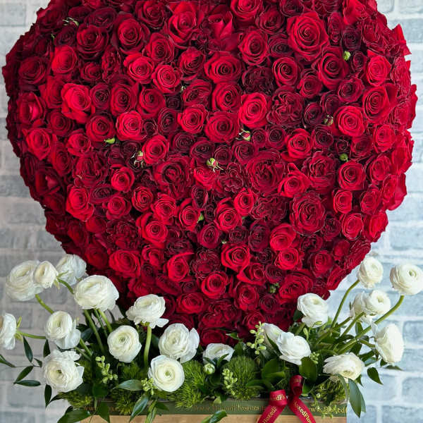 Heart-shaped red rose arrangement with white flowers at the base